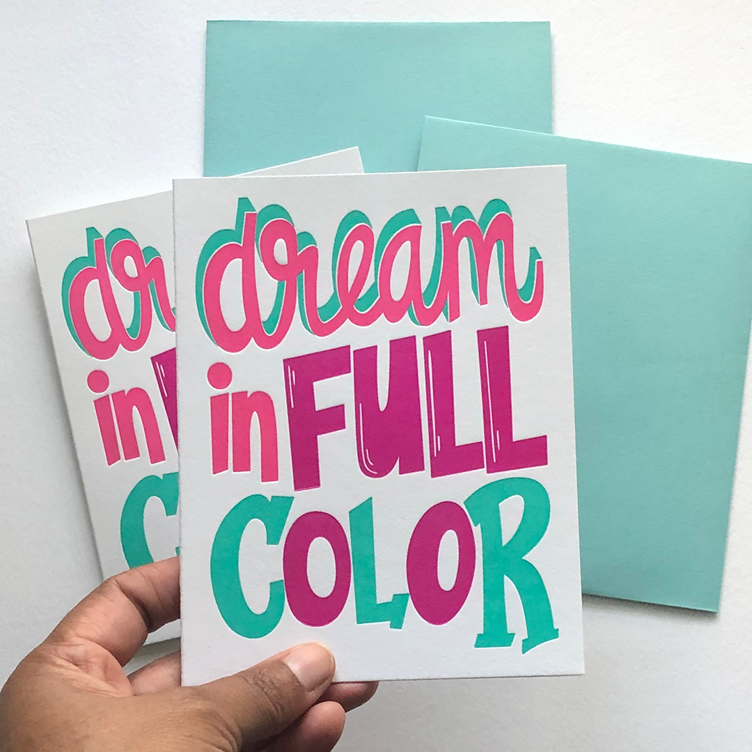 A hand holding a greeting card with the words dream in full color
